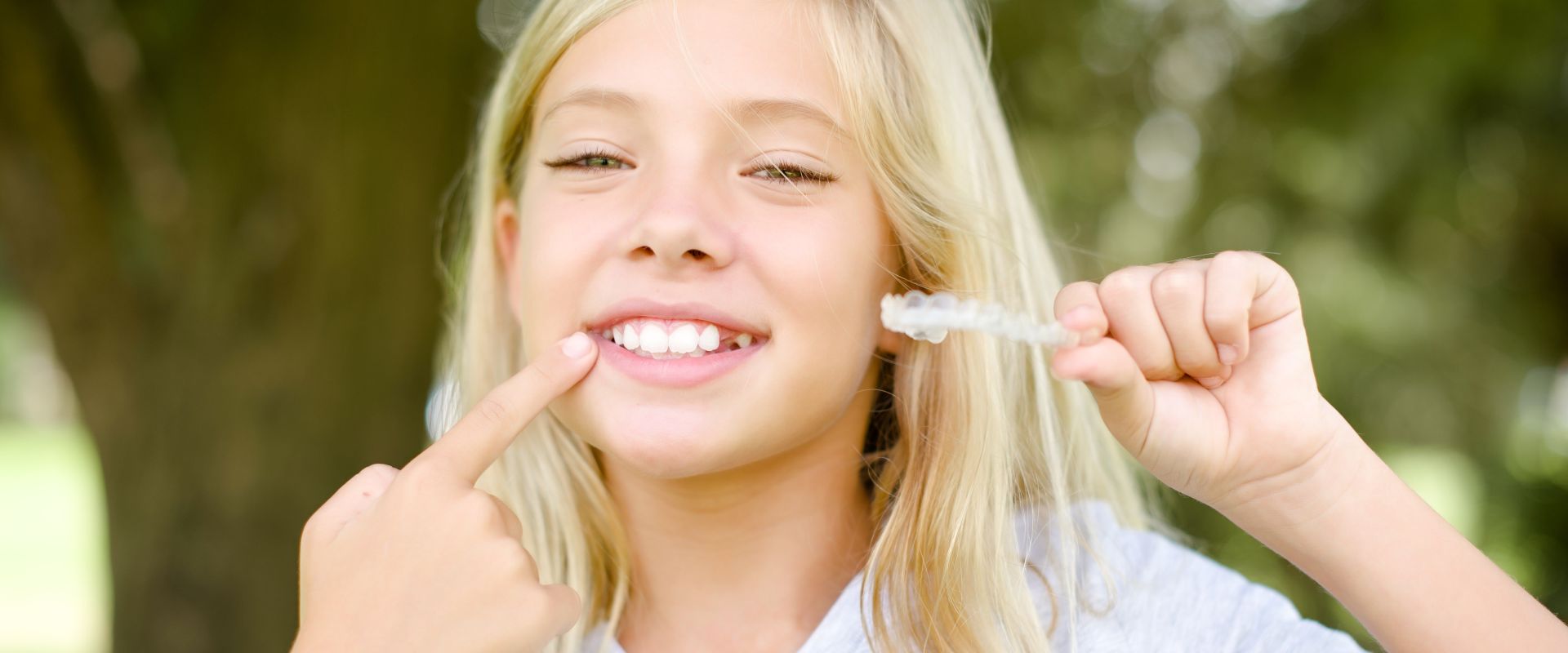 Mädchen mit unsichtbarem Invisalign Retainer in der Hand